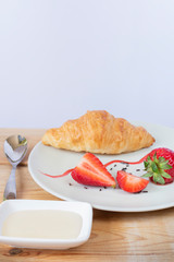 Delicious croissant breakfast served with strawberries and honey. pastry concept.