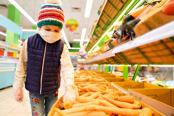 kid girl in medical mask gloves buys vegetables