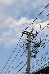 Closeup of electricity wire, cable, poles and high voltage transformer beside the street with cloudy blue sky background. Vertical view.