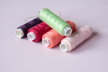 Sewing reinforced threads of different colors on a pink background