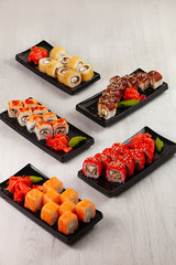 Hand holds chinese chopsticks with sushi on food background