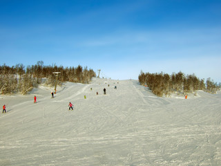 Ski slope in a picturesque place in the rays of the setting sun. Family holidays in European ski resorts.