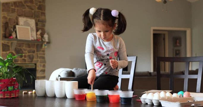 Lovely little girl dyeing easter eggs for the first time 