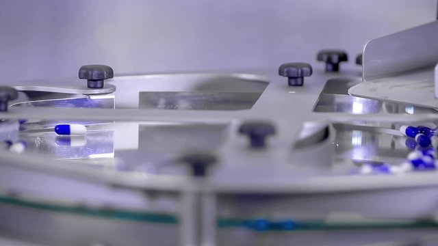 Blue pills spinning quicky on a plate during packaging process in the pharmaceutical lab