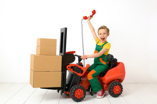 A boy in a forklift like a warehouse worker, supplier, courier.