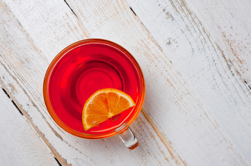 Glass cup with tea and lemon standing on a white painted wooden surface. Background for hot drinks. Soft and tonic drinks.