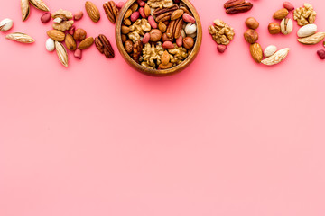 Fototapeta na wymiar Mixed nuts in bowl on pink background top-down frame copy space