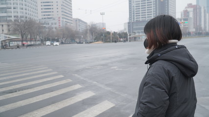 Fototapeta premium On March 3, 2020 in Shandong, China. Coronavirus pandemic. Woman with face mask walking on an empty street