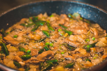 Fry on a small fire an assortment of different frozen vegetables with peas, asparagus, mushrooms and zucchini.