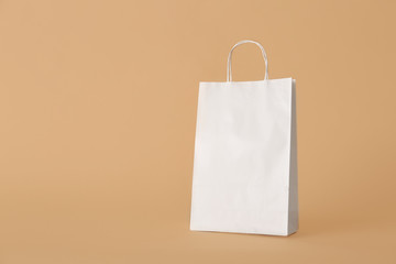 Paper shopping bag on color background