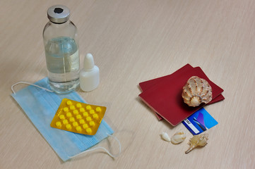 medicines and a medical mask lie opposite shells, passports and tickets. Concept of lost leave during illness or epidemic. Selective focus