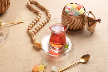 Fototapeta na wymiar Tasty Turkish tea with sweets and tasbih on color background