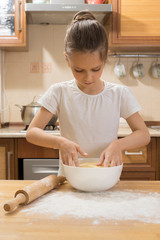 beautiful girl with long curly hair rolling dough in the kitchen