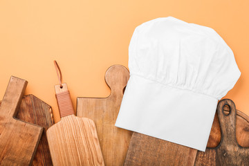 Composition with chef's hat and wooden boards on color background