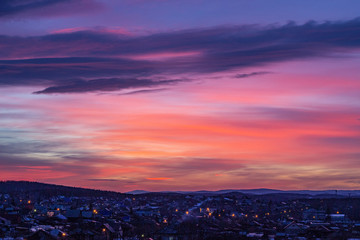 Beautiful purple sunset over the night city. Bright orange sunset in the evening city. Bright lights of urban houses. Soft focus. Russia, Ural