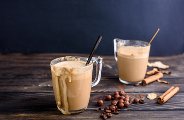 Delicious and fragrant dalgona coffee in glass cups, cinnamon sticks, dried mushrooms, a spoon of instant coffee, sugar.