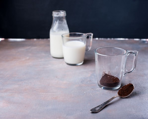 Brewing coffee in a glass cup, a jet of hot water, milk in a bottle, a spoon with custard coffee