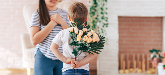 Boy holding a bouquet of flowers behind his back, the son gives his mother flowers, what to present...