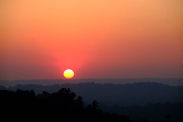 Beautiful sunset over a misty mountains. View of valley with silhouette of mountains ridge on backdrop.