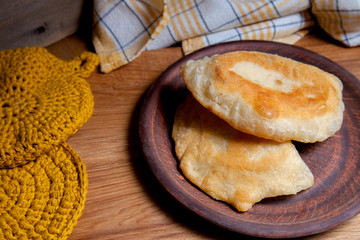 Clay plate of fried meat pies on wooden table.