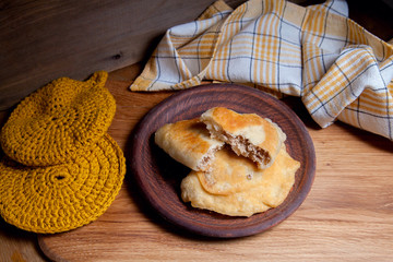Clay plate of fried meat pies on wooden table.