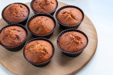 Homemade muffins on a wooden board near the window