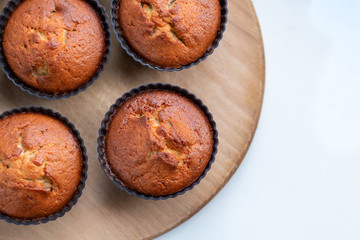 Homemade muffins on a wooden board near the window