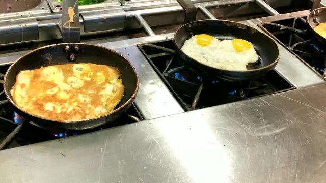 Cooking omelettes and fried eggs. Breakfast buffet in restaurant in hotel. 4K