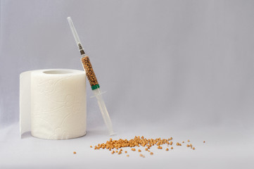 a roll of toilet paper and a syringe with buckwheat on a light background. Self-isolation, quarantine, panic on the background of coronovirus. Care of health. Pandemic.