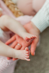 Close-up. Beautiful young mother holds in her hands the legs of her little daughter. Baby. Newborn.