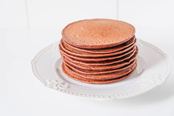 Sugar free protein chocolate pancakes stacked on white plate.