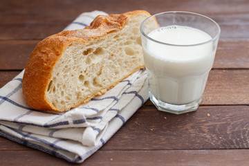 piece of freshly baked bread on a towel and a glass of milk