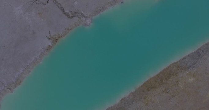 Aerial view of turquoise pool of water in a kaolin quarry.