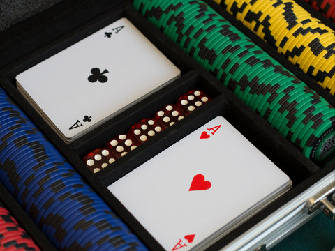 stacks of colorful poker chips and cards in case on green cloth in casino gambling chance