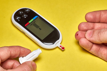 A diabetic checks his blood sugar. Close up man hands self-tested with a Lancet and a glucometer at home.