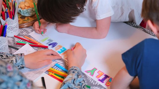 Psychological relaxation during a viral infection of COVID 19. Creative affairs in the family at home in self-isolation. Mom with children draws paper. Home education. Organization of a family school