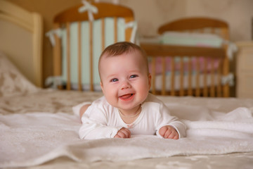 A newborn baby is lying at home in bed smiling.