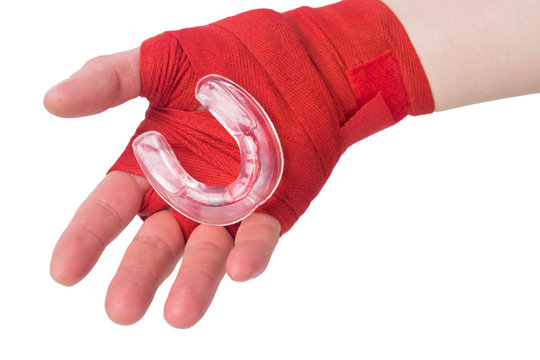 athlete's hand holds a mouth guard for protecting teeth during a fight isolated on white