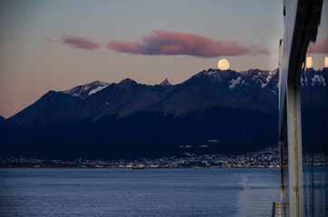 Amazing and breathtaking full moon scenery over Patagonia during early morning with city of...