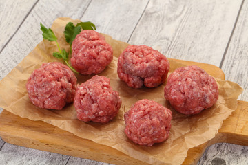 Raw meatball over wooden background