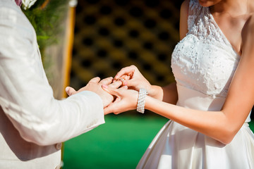 Wedding ceremony, bride puts wedding ring on hand of groom. Newlyweds couple