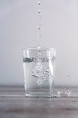 Throwing drops of water from above into a glass of water. Drink macro photography