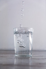 Throwing water into a glass of water on a white background. Drink macro photography