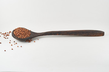 Wooden spoon with buckwheat on white background 