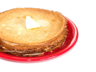 Staple of wheat golden yeast pancakes or crepes on red plate on a white background closeup