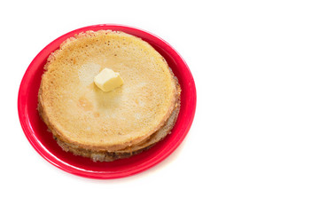Staple of wheat golden yeast pancakes or crepes on red plate on a white background closeup