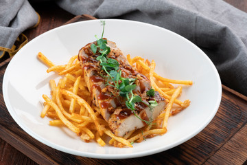 Chicken fillet cut into pieces with French fries on a white plate, a dish for lunch