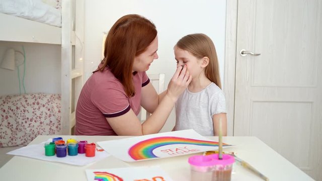 mom draws daughter of rainbow on cheek. stay home.