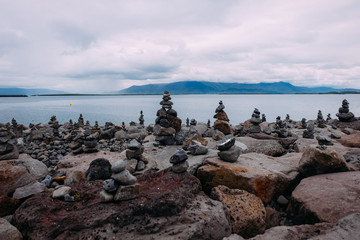 small stone towers on the coast with a fjord feed in Iceland in summer on a cloudy day