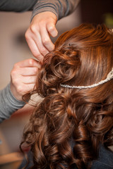 Hairdresser doing a woman's hair in professional hairdressing salon or barbershop , seen from behind the customer, unrecognizable.